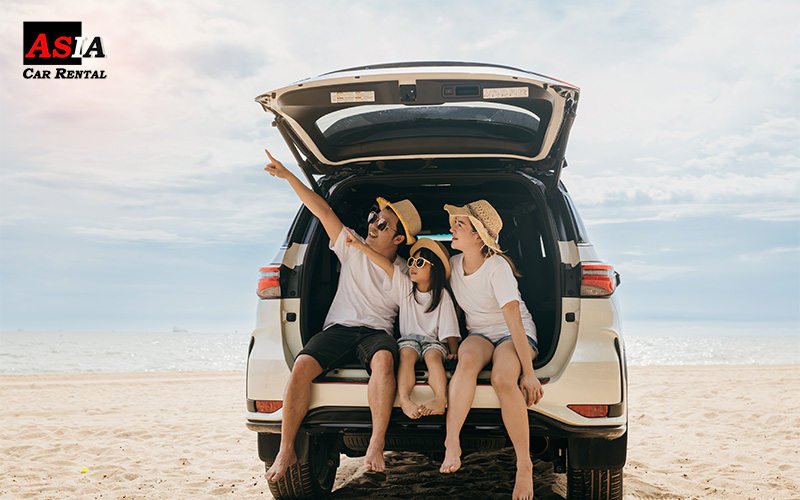 A family on holiday sitting in a car boot at the beach