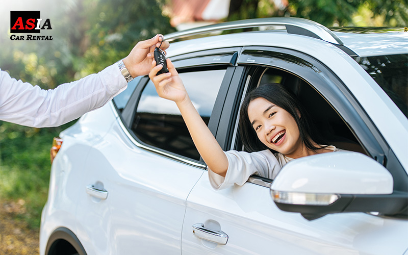 woman reaching for the key to her brand new car