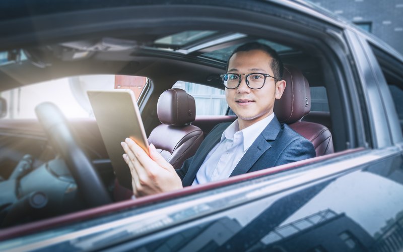 Businessman-holding-tablet-inside-a-company-car-in-Singapore