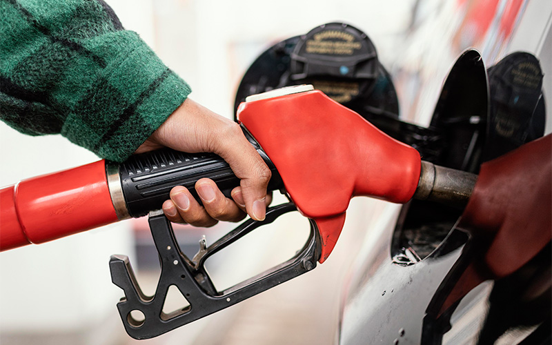 hand-holding-red-fuel-nozzle-refueling-car